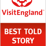 A logo for Visit England's Best Told Story Award. There's a graphic of a red rose on a white background at the top and a red block at the bottom with 'Best Told Story' written on it.